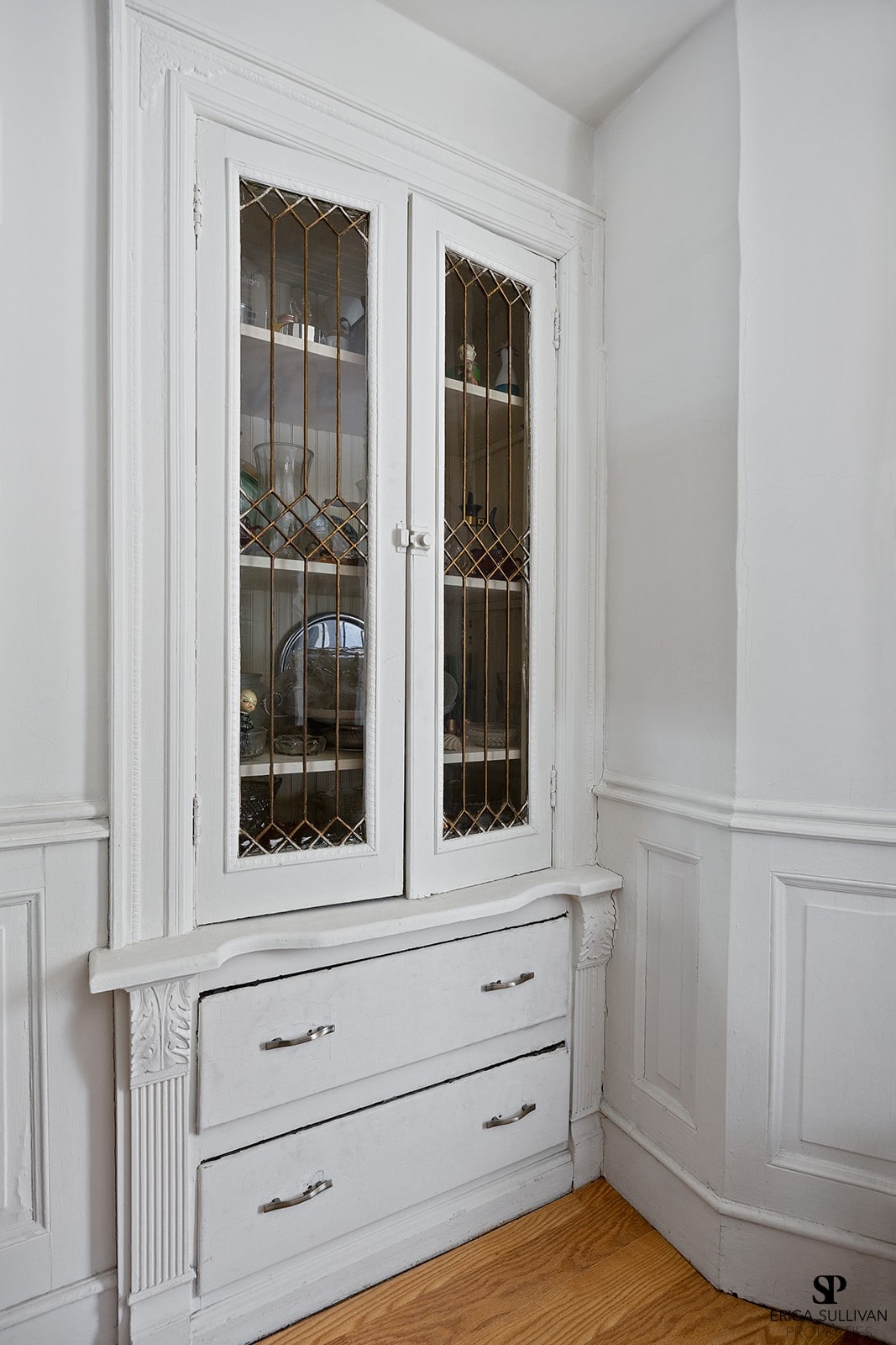 A white cabinet with glass doors and drawers.