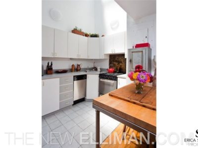 A kitchen with white cabinets and tile floors.