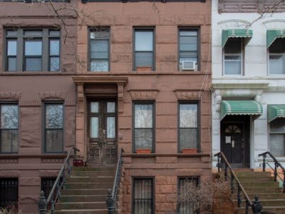 A row of three story buildings with steps leading to them.