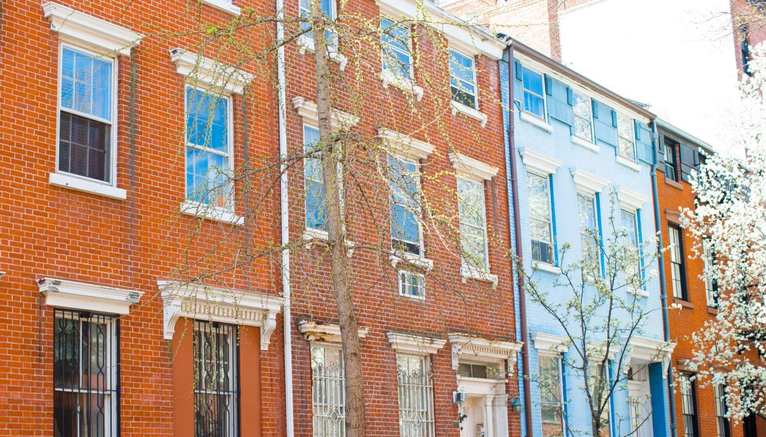 A row of brick buildings with windows and shutters.