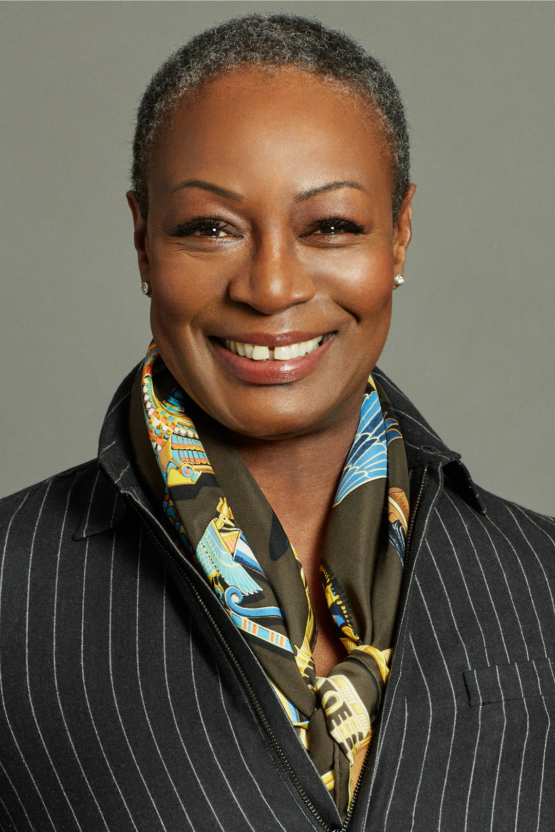 A woman with short hair wearing a black jacket and floral scarf.