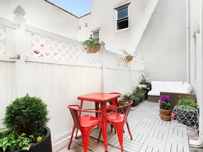 A patio with red chairs and white walls.