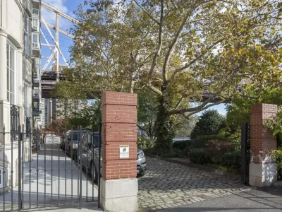 A gated driveway with trees and a bridge in the background.