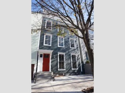 A building with a red door and a tree in front of it.